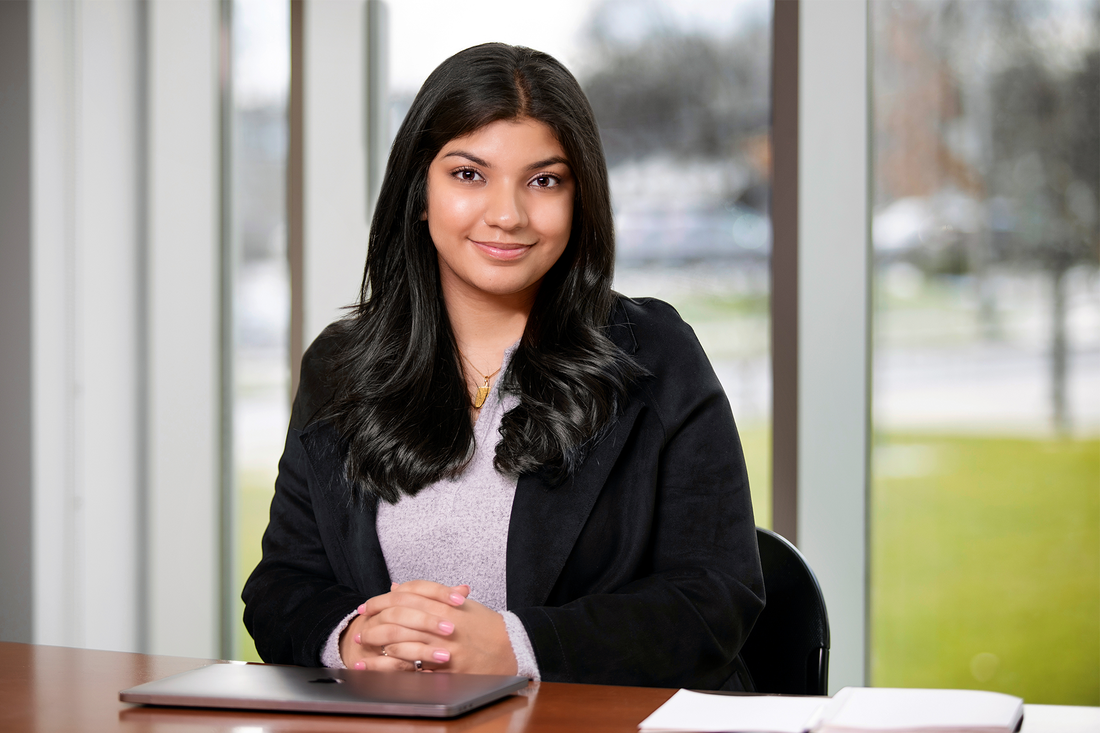 Gradute student Zainab Kumandan sitting and smiling.